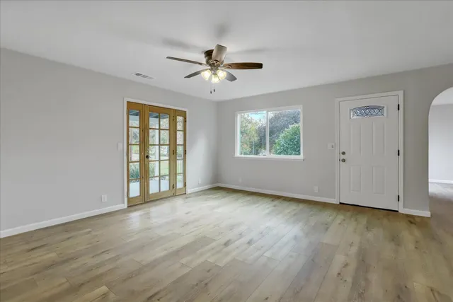 an empty room with wooden floor and windows