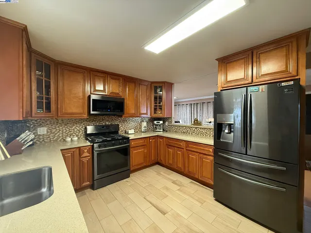 a kitchen with stainless steel appliances granite countertop a refrigerator stove top oven and sink