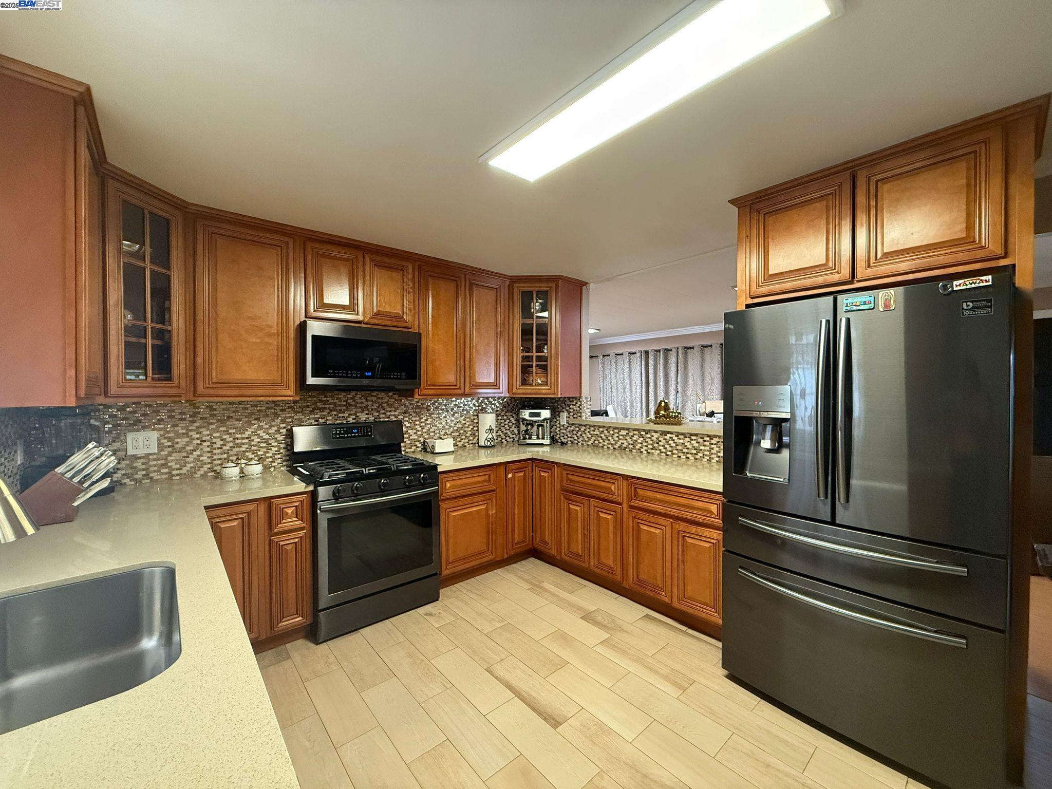 a kitchen with stainless steel appliances granite countertop a refrigerator stove top oven and sink