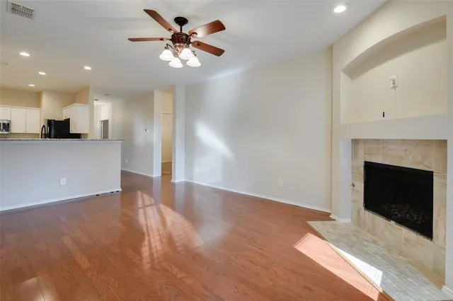 a view of an empty room with a fireplace and a kitchen view