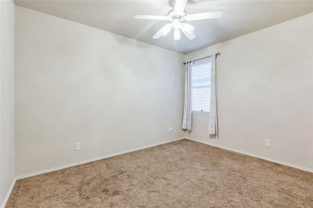 an empty room with a chandelier fan and windows