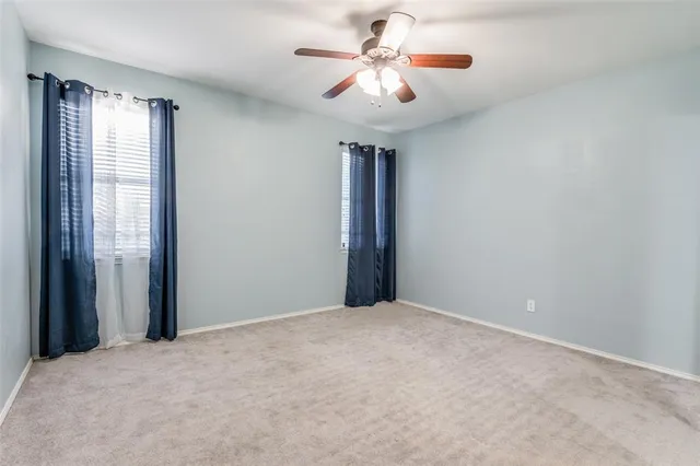 a view of an empty room with chandelier fan