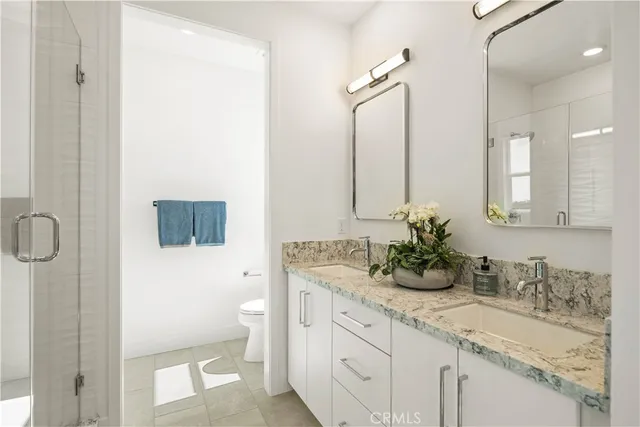 a bathroom with a granite countertop sink a toilet and mirror