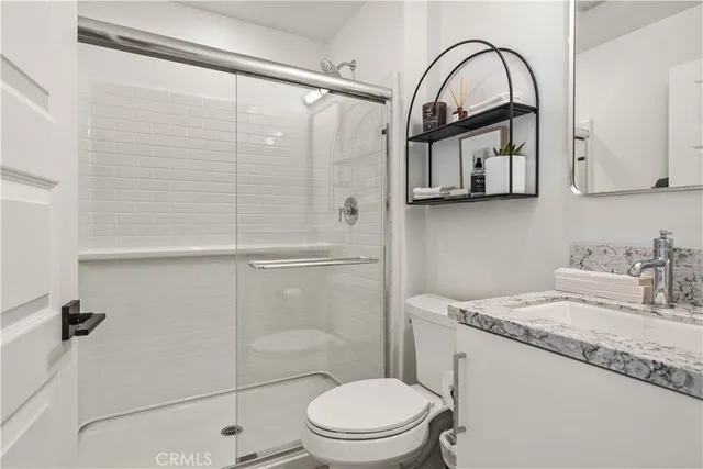 a bathroom with a granite countertop sink mirror vanity and toilet