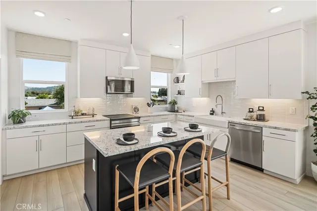 a kitchen with kitchen island granite countertop a sink a stove a dining table and chairs