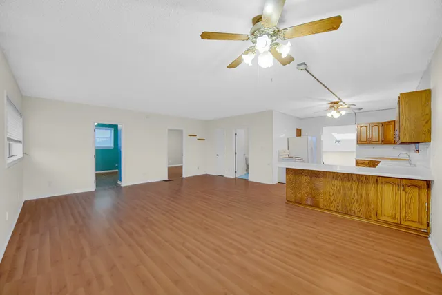 a view of an empty room with window and wooden floor