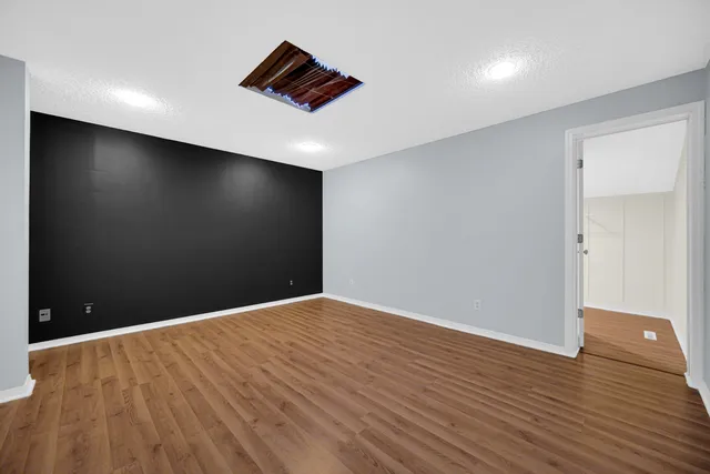 a view of an empty room with wooden floor and a ceiling fan