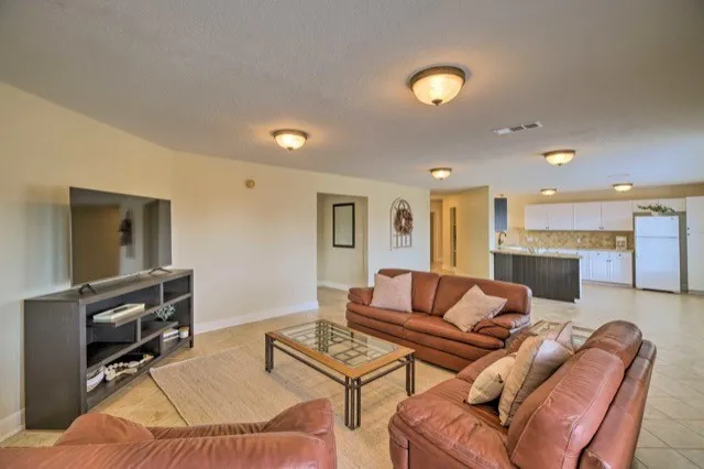 a living room with furniture a flat screen tv and kitchen view