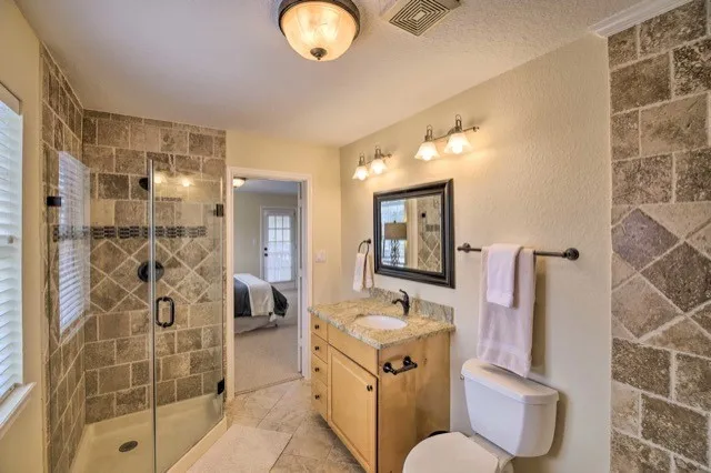 a bathroom with a double vanity sink a toilet a mirror and shower