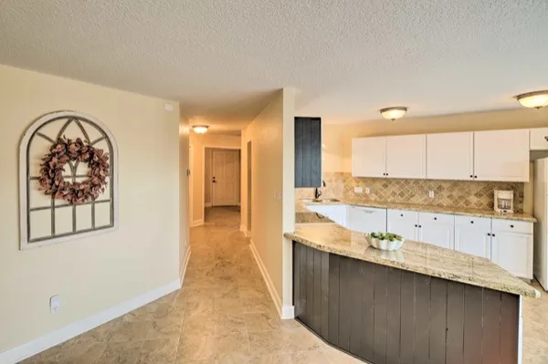 a view of a kitchen with kitchen island a sink wooden floor and a large window