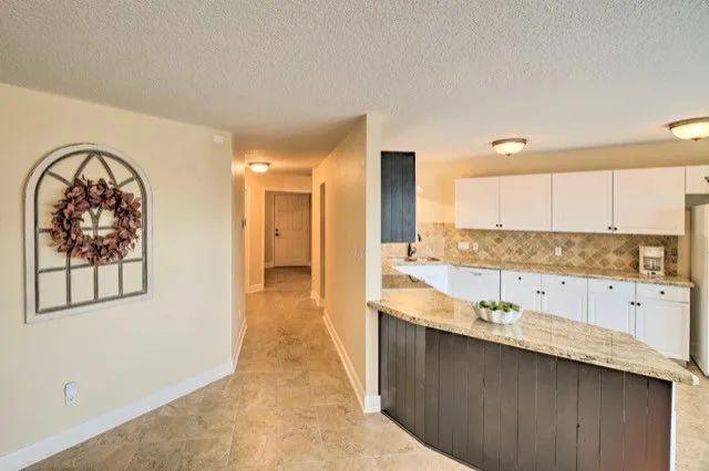 a view of a kitchen with kitchen island a sink wooden floor and a large window