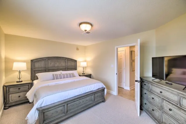 a bedroom with a large bed and flat tv screen on dresser