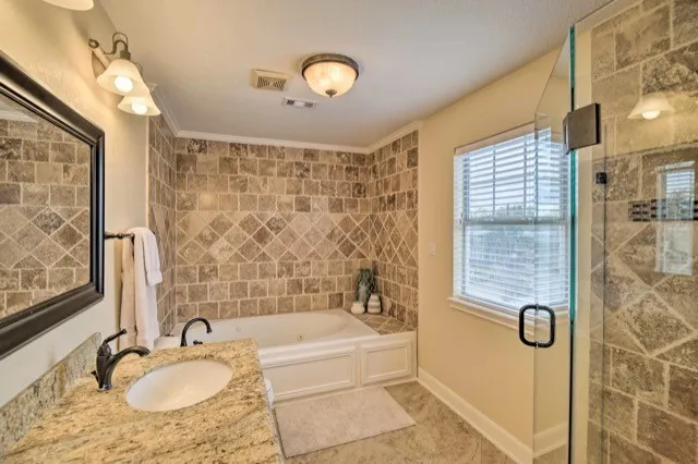 a bathroom with a granite countertop sink a mirror a bathtub and shower