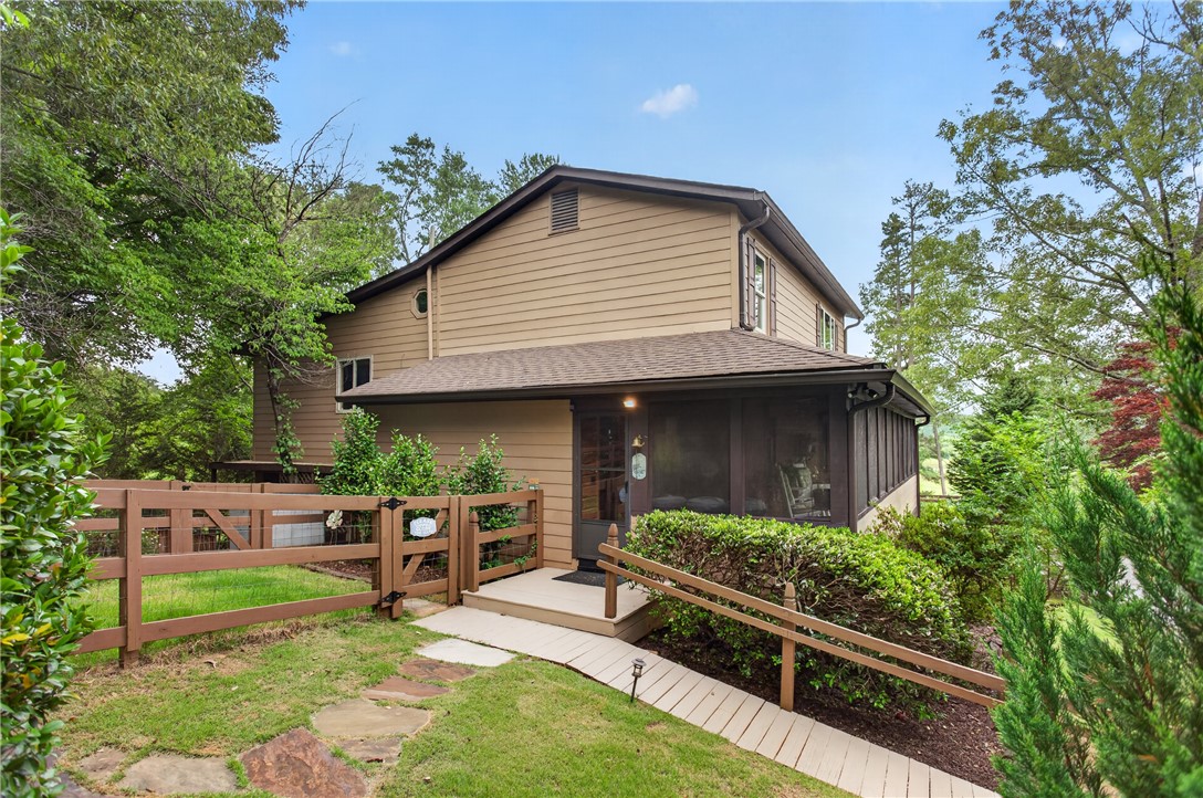 351 River Road Westminster, SC 29693 - Photo 2 of 50 A charming residence with inviting screened porch, wooden fence, and lush green landscaping.