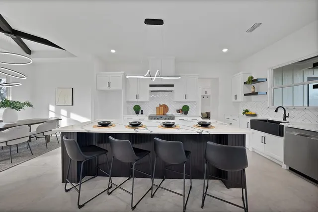 a kitchen with white cabinets and chairs