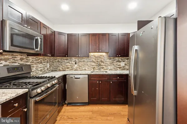 a kitchen with stainless steel appliances granite countertop a refrigerator stove and sink