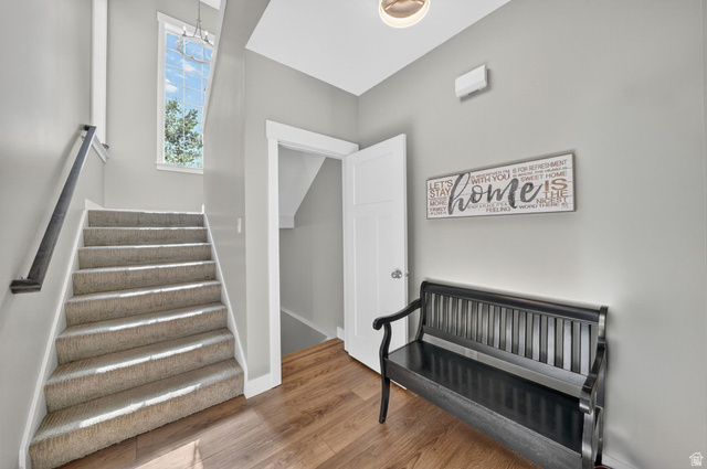7872 Farm House Lane Midvale, UT 84047 - Photo 4 of 39 Entryway & Staircase featuring carpeted treads, a dark handrail, and an overhead window providing natural light