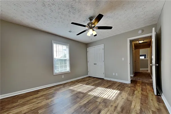 a view of empty room with wooden floor and fan