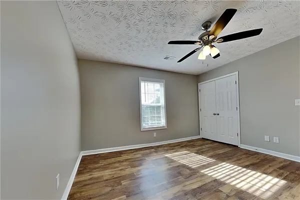 a view of empty room with wooden floor and fan