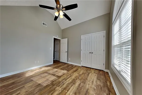 a view of empty room with wooden floor and fan