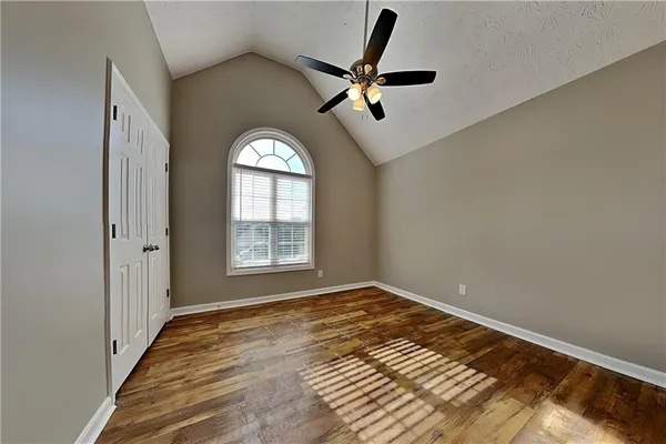 a view of empty room with wooden floor and fan