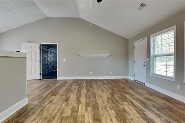 a view of an empty room with wooden floor and a window