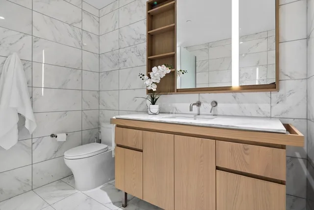 a bathroom with a granite countertop sink a toilet and a mirror