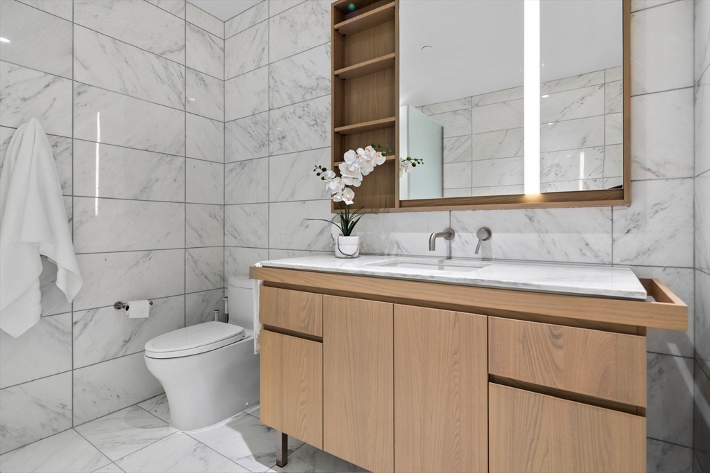 40 Trinity Place, Unit U25D Boston, MA 02116 - Photo 8 of 12 a bathroom with a granite countertop sink a toilet and a mirror