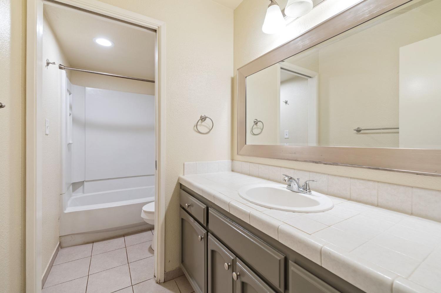 7675 North First Street, Unit 136 Fresno, CA 93720 - Photo 15 of 40 a bathroom with a sink a shower and a mirror