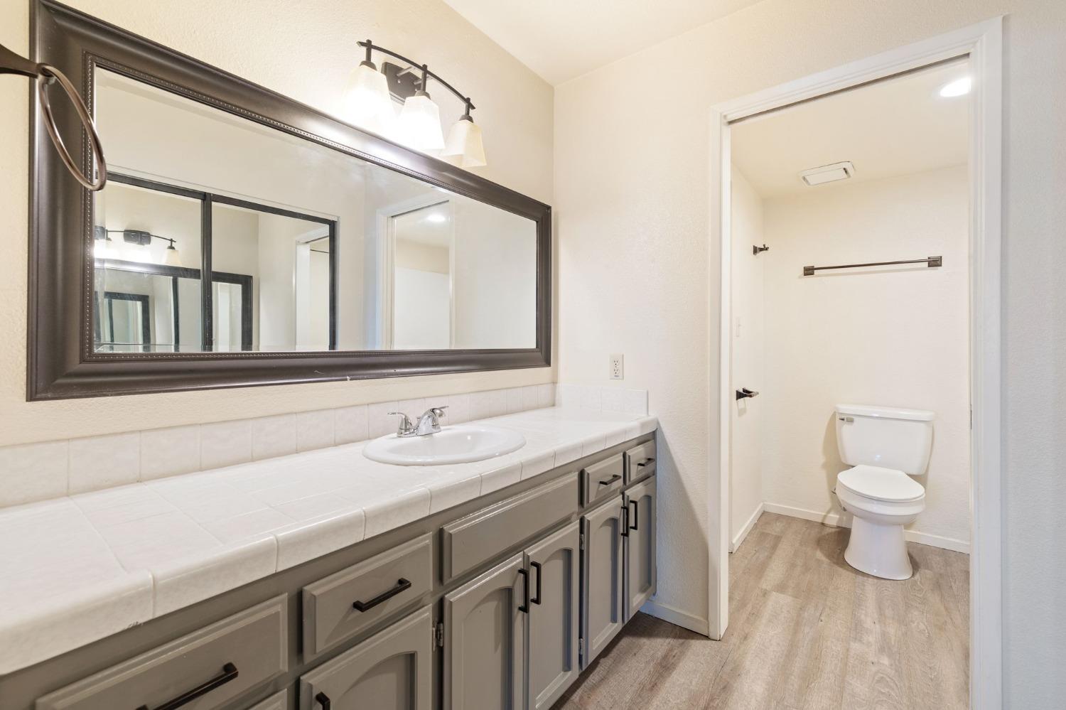 7675 North First Street, Unit 136 Fresno, CA 93720 - Photo 19 of 40 a bathroom with a sink a toilet and a mirror