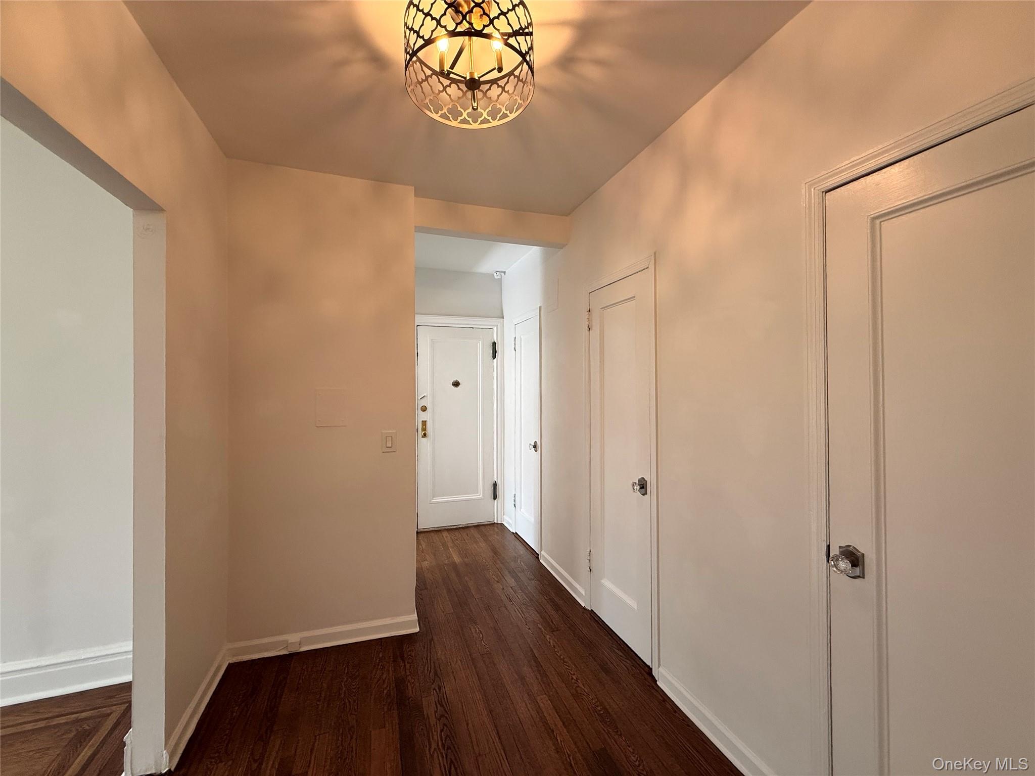 143 Garth Road, Unit 3L Scarsdale, NY 10583 - Photo 13 of 37 The property features dark hardwood flooring and a stylish overhead light fixture, illuminating the hallway