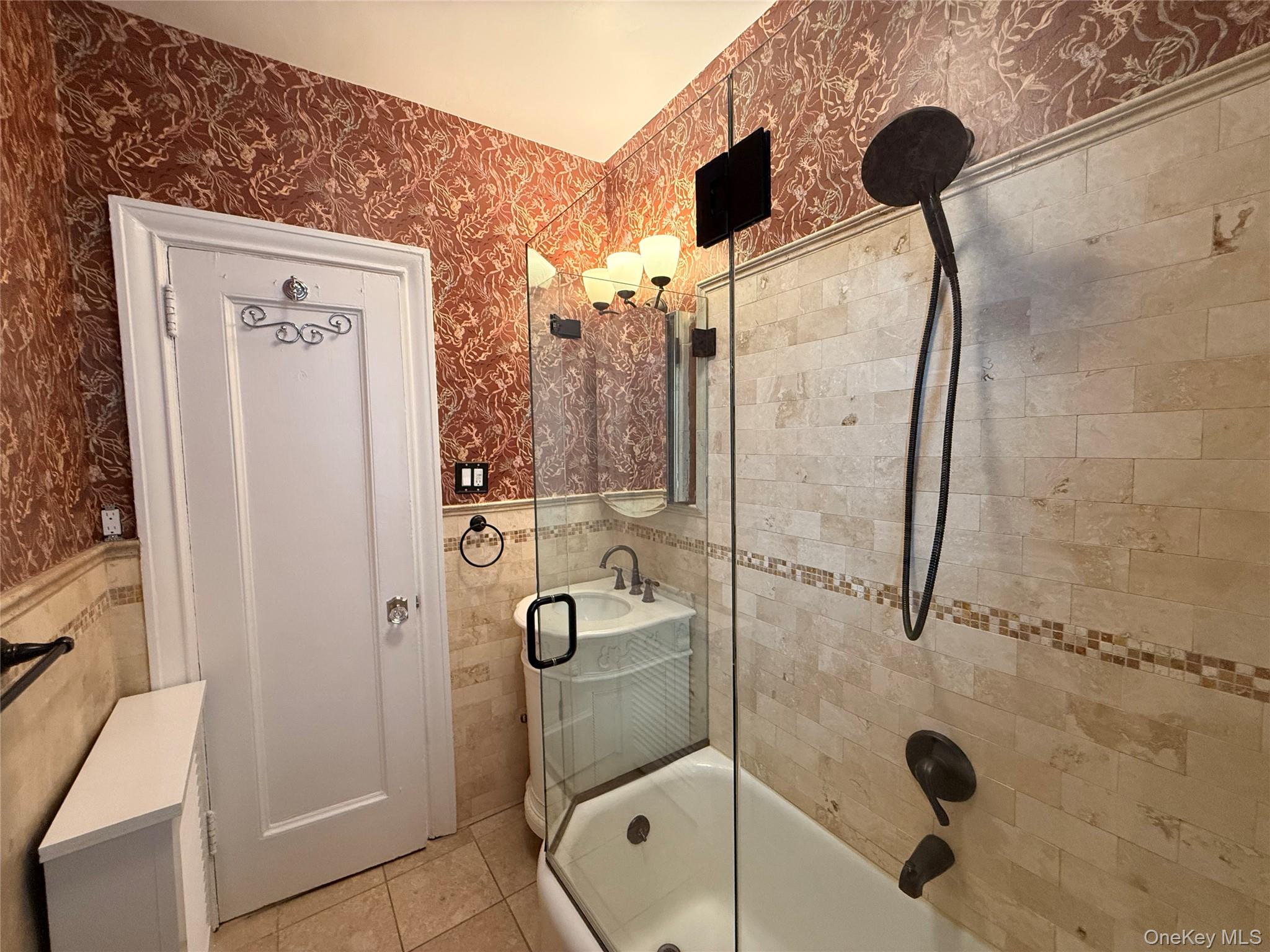143 Garth Road, Unit 3L Scarsdale, NY 10583 - Photo 17 of 37 Bathroom featuring a tiled shower with a glass enclosure, a vanity with a vessel sink, and patterned wallpaper