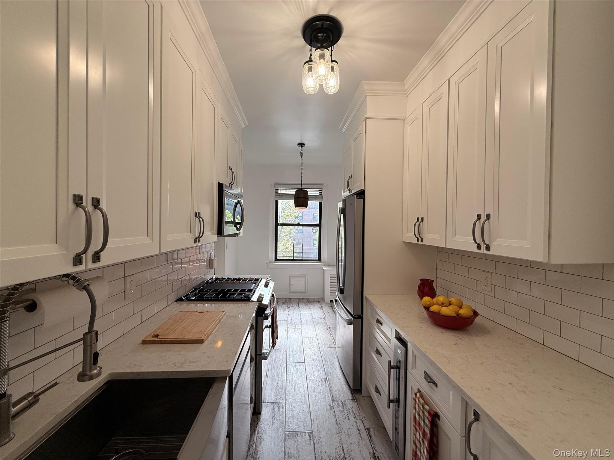 143 Garth Road, Unit 3L Scarsdale, NY 10583 - Photo 27 of 37 The kitchen features white shaker-style cabinetry, stainless steel appliances, light-colored countertops, and a subway tile backsplash