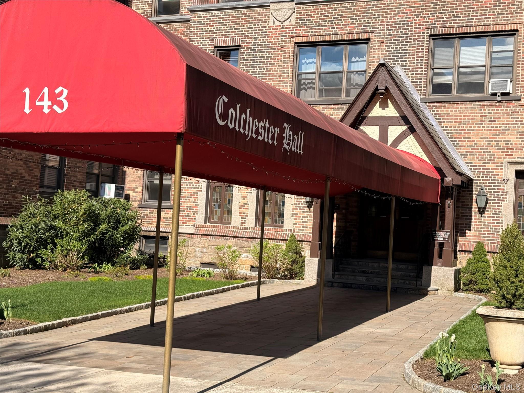 143 Garth Road, Unit 3L Scarsdale, NY 10583 - Photo 36 of 37 The property features a brick exterior with a decorative entrance, a red awning, and a paved walkway