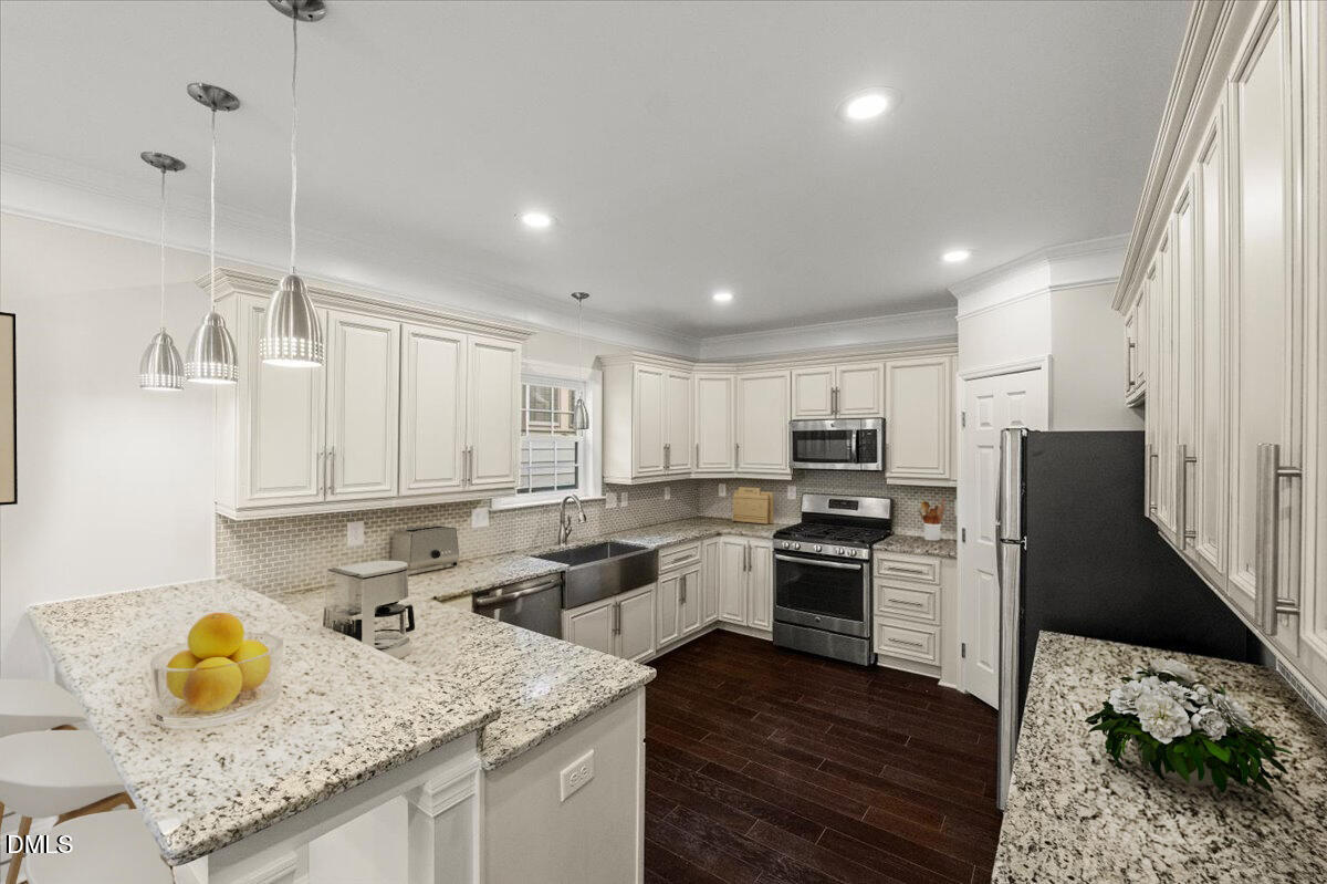 2402 Green Street Durham, NC 27705 - Photo 3 of 25 a kitchen with granite countertop a sink stainless steel appliances and white cabinets