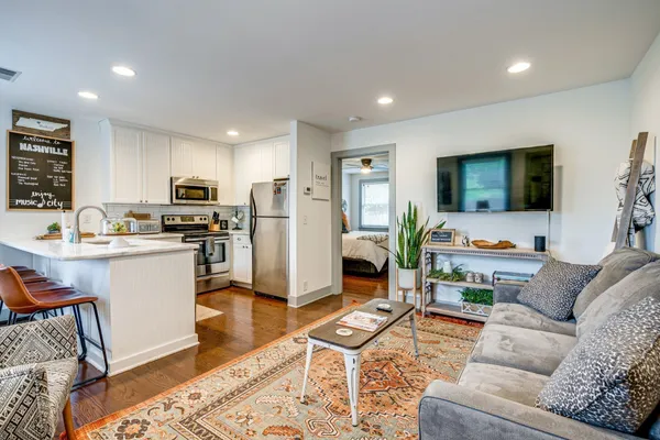 a living room with furniture kitchen view and a window
