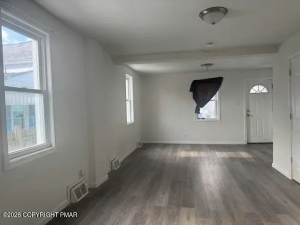 an empty room with wooden floor and windows
