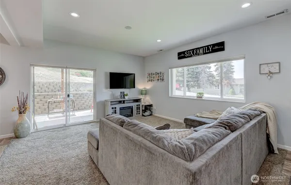 a living room with furniture a flat screen tv and a floor to ceiling window