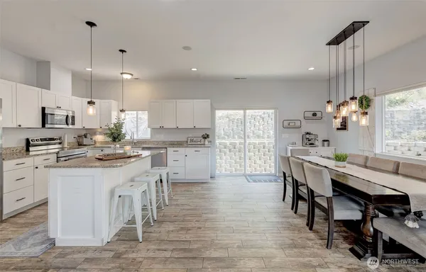a kitchen with stainless steel appliances kitchen island granite countertop a table chairs sink and cabinets