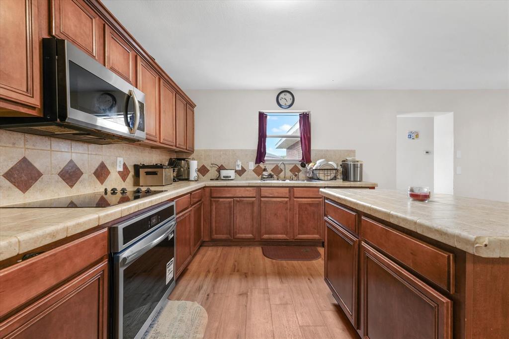 6725 Prairie Fire Road Arlington, TX 76002 - Photo 12 of 31 a kitchen with stainless steel appliances granite countertop a sink stove and microwave