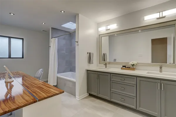 a spacious bathroom with a double vanity sink a large mirror and a bathtub