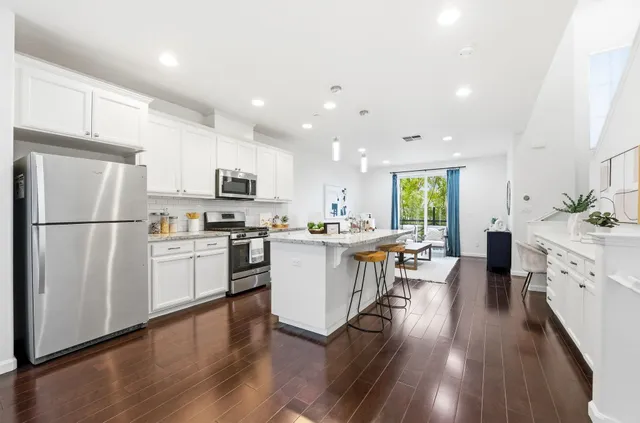 a kitchen with a refrigerator a stove top oven a sink dishwasher and white cabinets with wooden floor