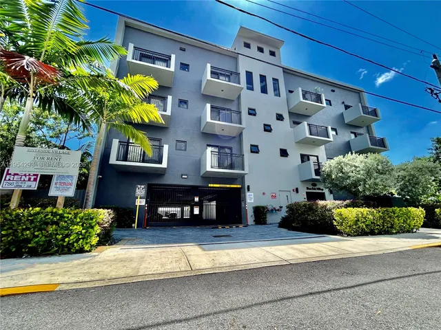 a front view of a building with a garden and plants