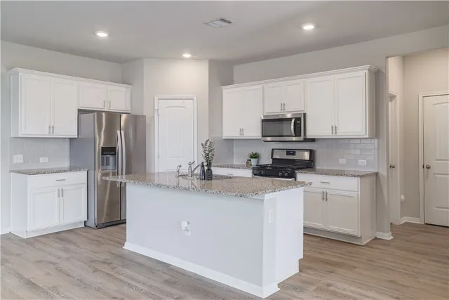 a kitchen with stainless steel appliances granite countertop a refrigerator stove microwave and sink