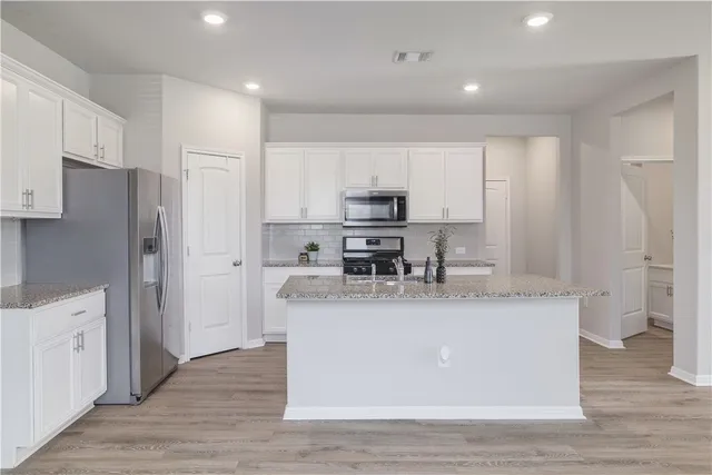 a view of a kitchen with stainless steel appliances granite countertop a stove a refrigerator a sink dishwasher and a refrigerator with wooden floor