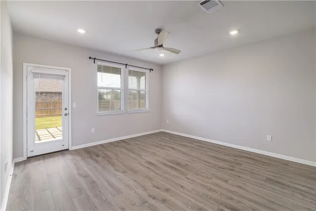 an empty room with wooden floor and windows