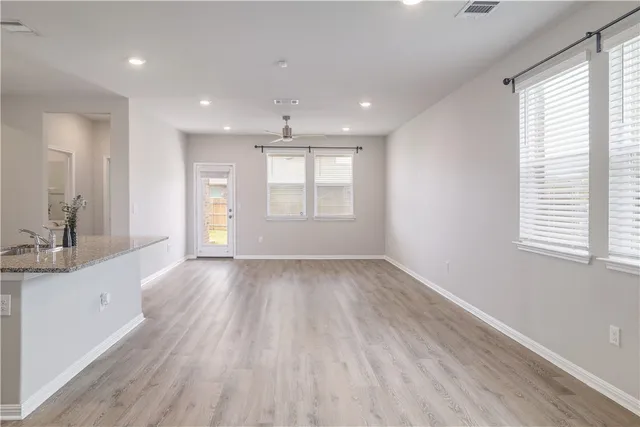 a view of an empty room with a window and wooden floor