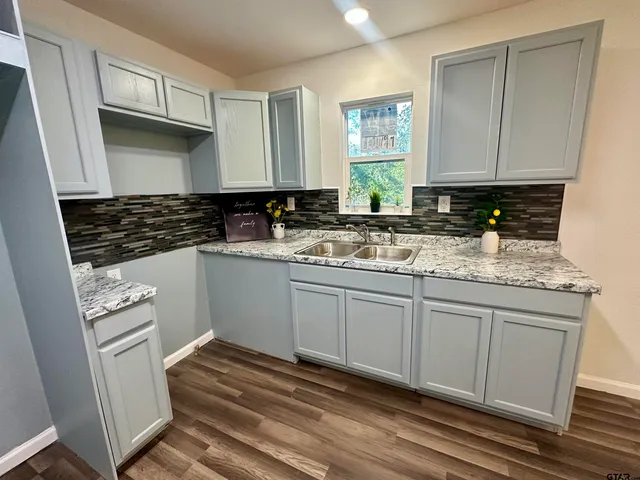 a kitchen with granite countertop a sink cabinets and stainless steel appliances