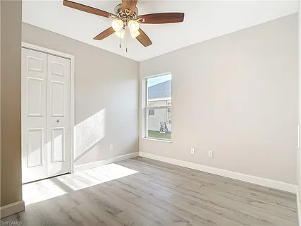 an empty room with wooden floor a ceiling fan and windows
