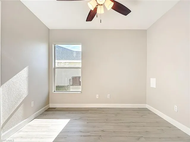 an empty room with wooden floor cabinet and windows